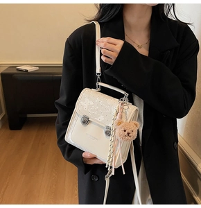 Detail of cream crossbody bag with butterfly embossing and teddy bear charm