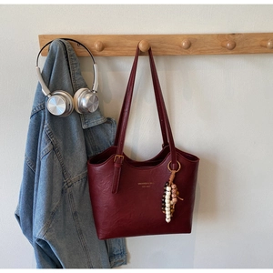 Macro detail of dark burgundy vintage leather tote bag with branded print and beaded charm