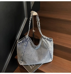 Macro detail of vintage washed blue denim tote bag with chain strap and fabric texture