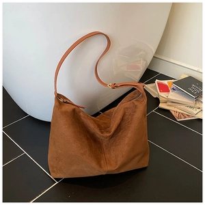 Détail du sac hobo en daim marron avec fermeture éclair dorée et style vintage chic