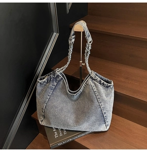 Detail of retro blue denim tote bag with metal chain strap on a wooden staircase
