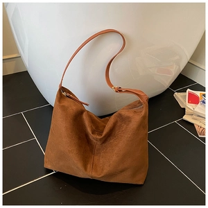 Détail d'un grand sac hobo en daim marron avec coutures verticales et finitions dorées