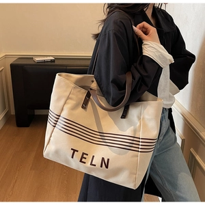 Detail of canvas tote bag with brown leather handles and striped pattern on beige fabric