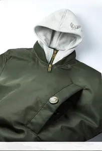 Detail of dark green bomber jacket with grey hood and bronze metal zipper closure