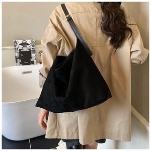 Détail d'un grand sac fourre-tout en daim noir avec une boucle dorée sur la bandoulière large