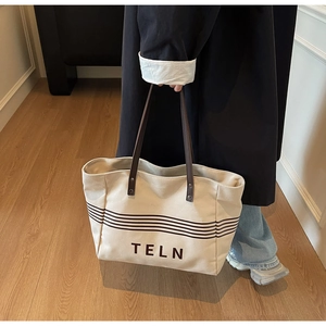 Detail of canvas tote bag with brown straps and striped TELN graphic print