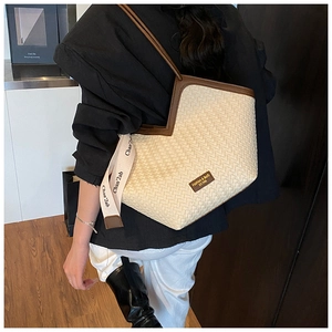 Detail view of woven tote bag with brown leather trim and retro branding tag