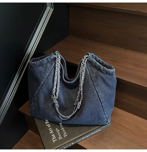 Detailed view of the dark blue denim tote bag with chic silver metal chain straps