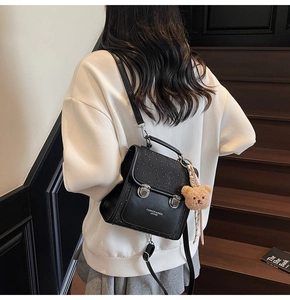 Detail of black PU leather backpack with sequin embossed flap and plush bear charm