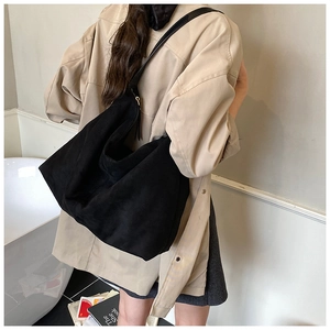 Minimalist large black tote bag in soft matte finish worn by model in a chic indoor setting