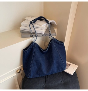 Close-up of woven metal chain strap on vintage dark blue denim tote bag texture