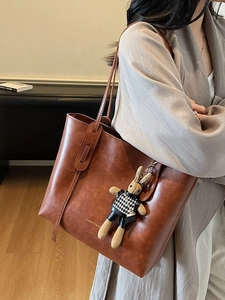 Brown vintage oil wax leather tote bag worn by a model with a cute rabbit pendant