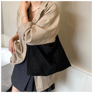 Détail de la texture mate douce et de l'effet drapé d'un grand sac cabas en daim noir