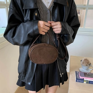 Minimalist brown suede round crossbody bag with leather strap styled for autumn fashion