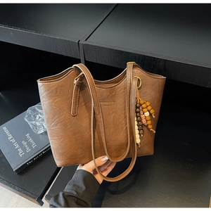 Detailed close-up of dark brown vintage tote bag with wooden bead charm and logo