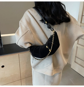 Detailed back view of a black matte crescent bag with a gold chain on a shoulder