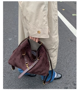 Detailed close-up of a large suede tote bag in dark brown with gold metal accents