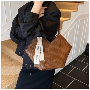 Brown woven tote bag with V-shaped opening and letter strap on a casual shoulder bag