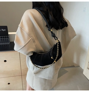 Detail of black suede hobo bag featuring gold chain trim and knotted leather strap