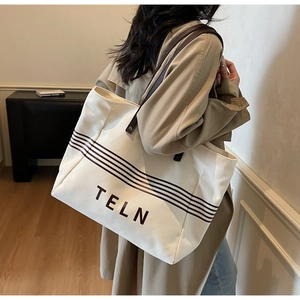 Model wearing a large canvas tote bag with brown stripes and leather straps for commuting