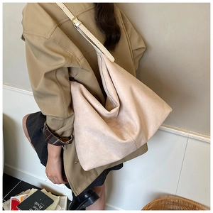 Gros plan détaillé du sac cabas en daim beige avec bandoulière en cuir blanc réglable