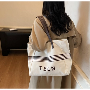 Canvas tote bag with leather straps worn by model showing large capacity and daily use size