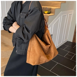 Sac fourre-tout en daim marron porté par un modèle dans un cadre épuré et lumineux
