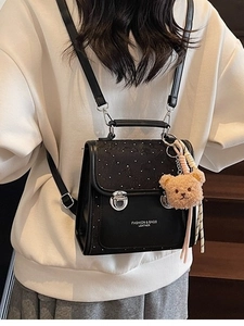 Fashionable black leather backpack with polka dots and a cute brown teddy bear keychain