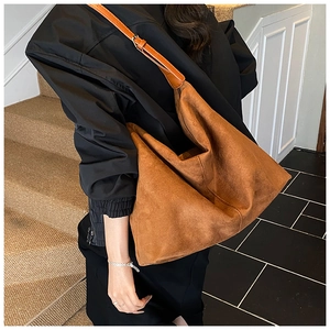 Detailed macro view of the caramel brown suede texture and adjustable strap on a tote bag