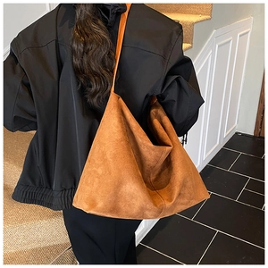 Grand sac cabas en daim marron caramel porté avec une veste noire classique