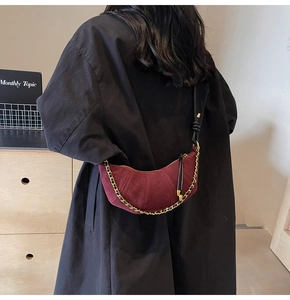 Close-up of burgundy frosted suede crescent bag with bold gold chain and leather strap