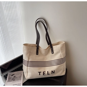 Detail view of canvas tote bag with TELN logo, brown straps and large capacity