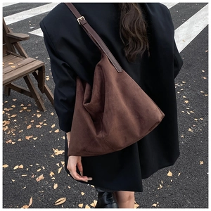 Sac hobo en daim marron avec bandoulière réglable porté par un mannequin en ville en automne