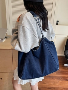 Large vintage dark blue denim tote bag with silver metal chain straps on female model