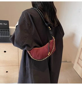 Detail of burgundy suede crescent bag with gold chain strap and knot shoulder strap