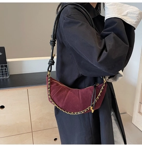 Detail of burgundy matte dumpling bag with golden chain and knotted shoulder strap