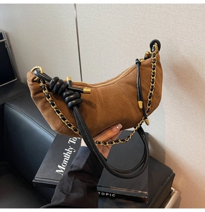Detail of a brown matte suede hobo bag with black leather knot and gold chain strap