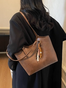 Brown large vintage tote bag with beaded charm accessory shown on model shoulder