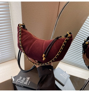Detail shot of the burgundy faux suede fabric and metallic chain on the crescent bag