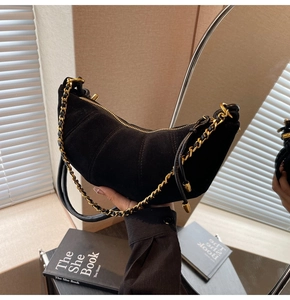 Close-up of black matte suede dumpling bag with gold zipper and woven chain detail