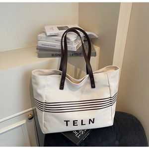 Close-up of canvas tote bag featuring brown horizontal stripes and TELN lettering