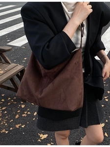 Grand sac cabas en daim marron foncé pour femme porté à l'épaule dans un cadre urbain