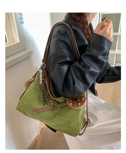 Detail of dark green suede tote bag with leather trim and colorful star bag charm