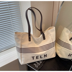 Detail view of canvas tote bag with leather handles and striped pattern via mirror reflection