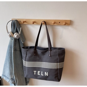 Detail of large canvas tote bag in dark grey with white stripes and TELN logo
