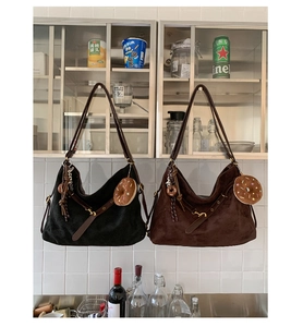 Detail of vintage suede tote bags in black and brown with donut plush charms