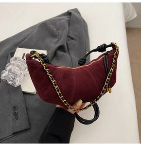 Detail of burgundy frosted leather dumpling bag with gold chain and knot shoulder strap
