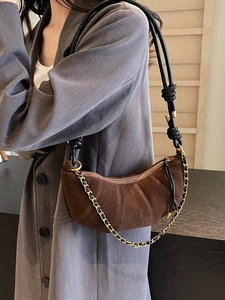 Brown suede dumpling bag with pleated texture and dual straps shown on a model's shoulder