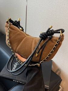 Brown suede croissant shoulder bag with quilted texture and knotted chain strap details