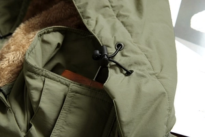 Detail of army green jacket showing drawstring hood with brown faux shearling lining